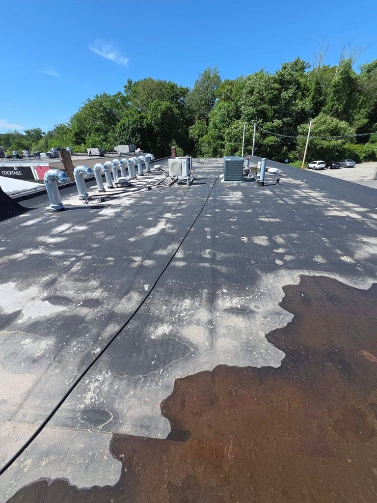 Commercial flat roof half-covered in rust-colored grime, half freshly washed clean